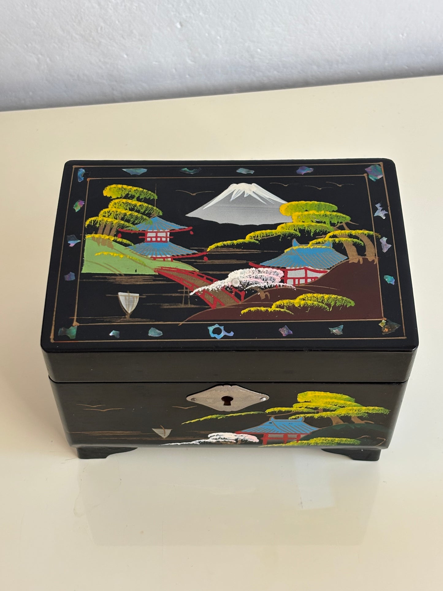 Small vintage music box with key, lacquered case and Mount Fuji on the mirror